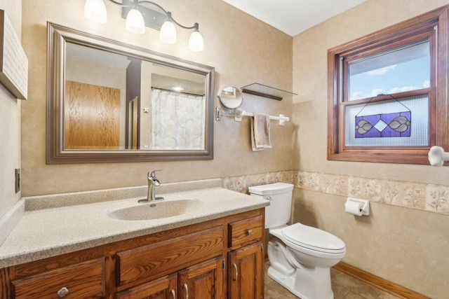 full bathroom featuring a wainscoted wall, vanity, toilet, and tile patterned floors