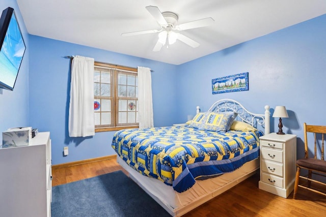 bedroom with a ceiling fan, baseboards, and wood finished floors