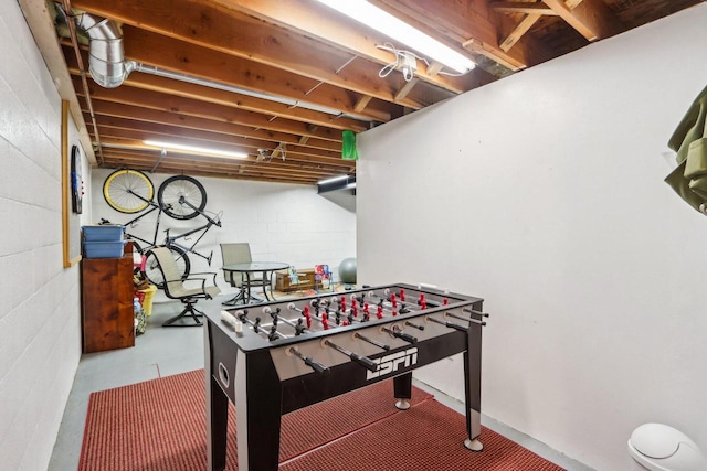 playroom featuring concrete flooring and concrete block wall