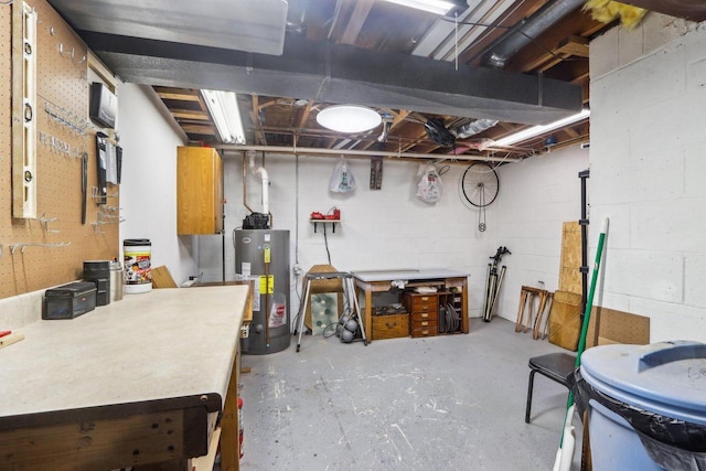 unfinished below grade area featuring water heater, a workshop area, and concrete block wall