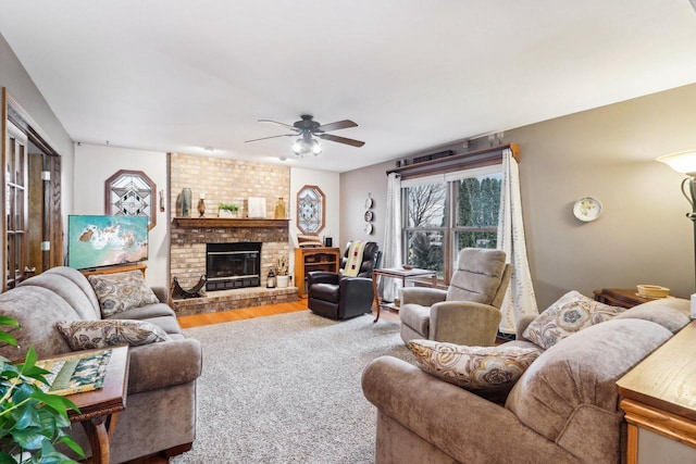 living room with a fireplace, a ceiling fan, and wood finished floors