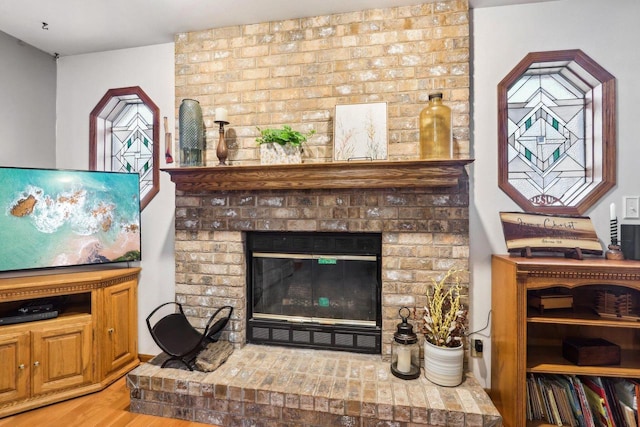 living room featuring a brick fireplace and wood finished floors