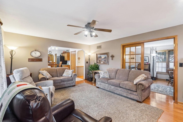 living room with light wood finished floors, visible vents, and a ceiling fan