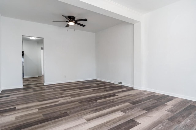 empty room featuring a ceiling fan, visible vents, baseboards, and wood finished floors