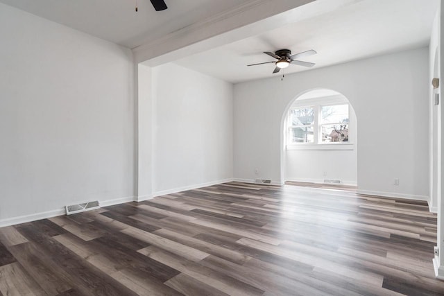 spare room featuring baseboards, visible vents, a ceiling fan, arched walkways, and wood finished floors