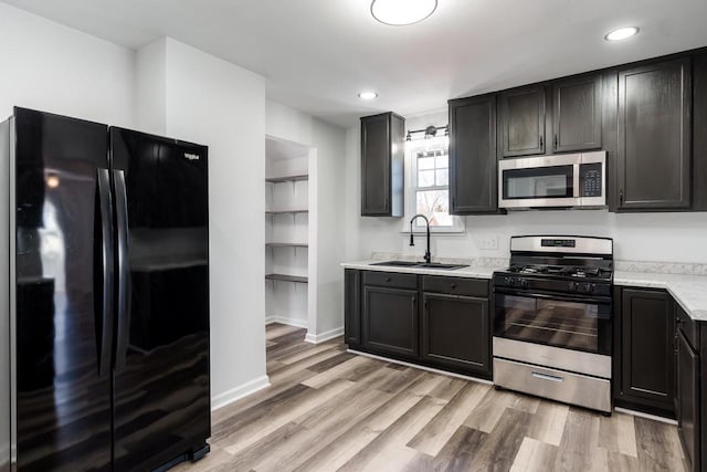 kitchen featuring light wood finished floors, recessed lighting, appliances with stainless steel finishes, a sink, and baseboards