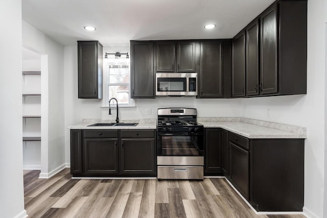 kitchen featuring stainless steel appliances, light countertops, a sink, and light wood-style flooring