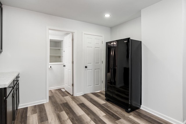 kitchen with dark wood-type flooring, freestanding refrigerator, light countertops, and baseboards