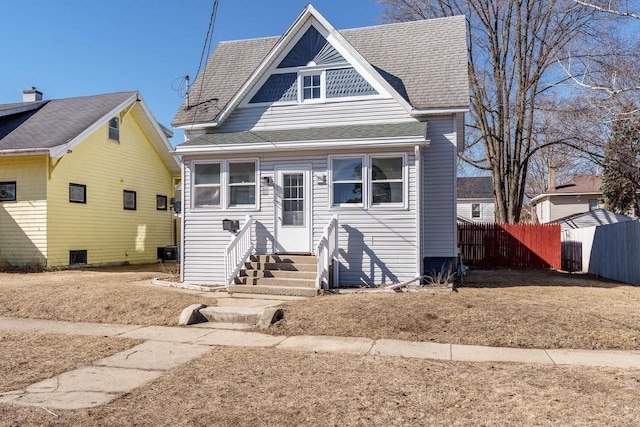 view of front of home featuring entry steps, a shingled roof, and fence