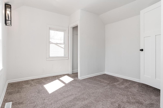 unfurnished bedroom with baseboards, visible vents, vaulted ceiling, and carpet flooring