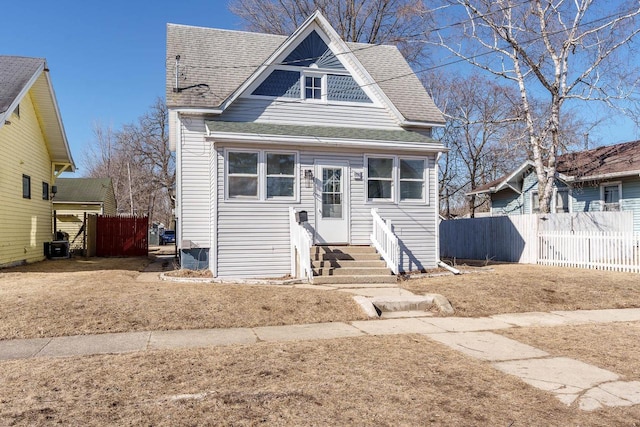 view of front of property featuring entry steps, a shingled roof, and fence