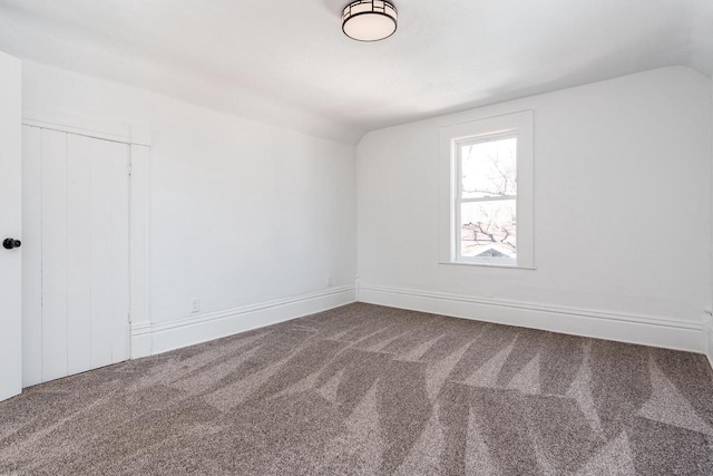 carpeted spare room with lofted ceiling and baseboards