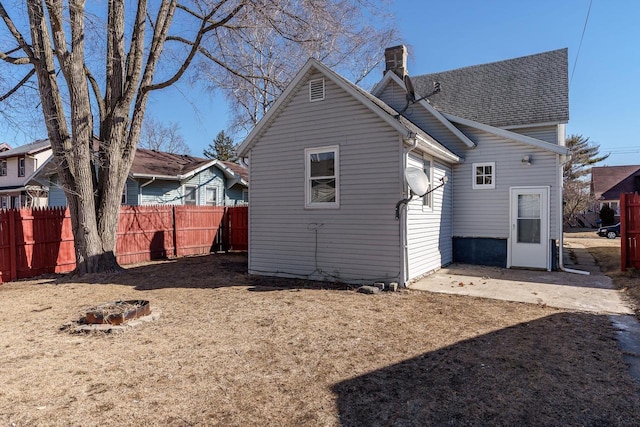 rear view of house with a chimney, fence, a patio, and roof with shingles