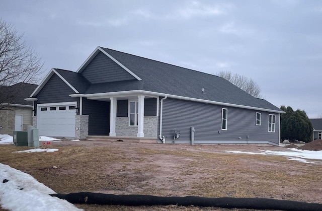 view of front of property with an attached garage, stone siding, and a shingled roof