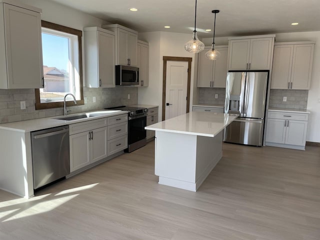 kitchen with appliances with stainless steel finishes, light countertops, light wood-style floors, and a sink