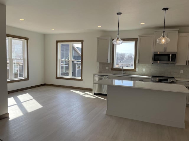 kitchen with a sink, stainless steel appliances, light wood-style floors, and light countertops