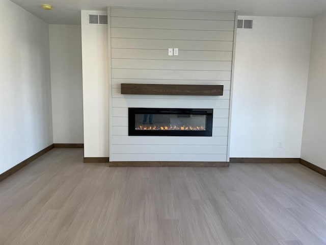 unfurnished living room featuring wood finished floors, visible vents, and baseboards