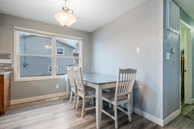 dining space with baseboards, visible vents, and light wood finished floors