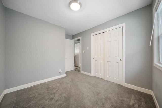 unfurnished bedroom with carpet floors, a closet, and baseboards