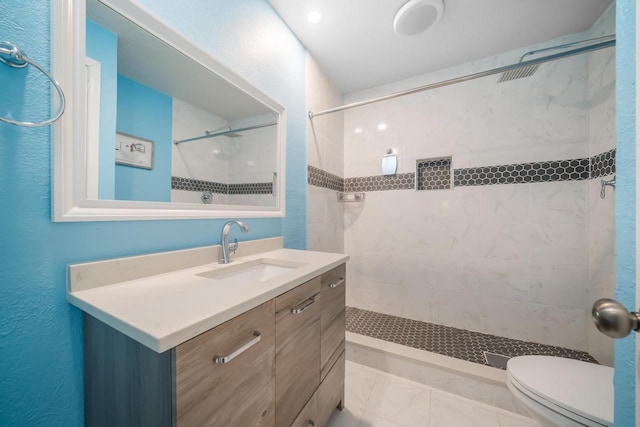 full bathroom featuring tiled shower, vanity, and toilet