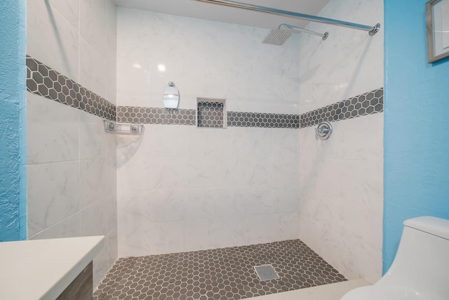 bathroom featuring toilet and a tile shower