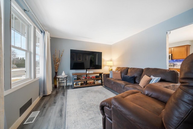 living room featuring visible vents, baseboards, and wood finished floors