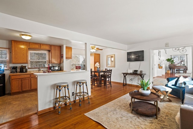 living room featuring a ceiling fan, baseboards, and wood finished floors