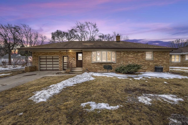 view of front of home featuring a garage, driveway, a chimney, and brick siding