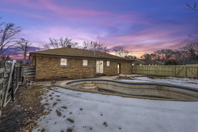 pool at dusk with a fenced backyard