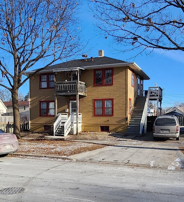 view of front of property with a balcony, stairs, and a chimney