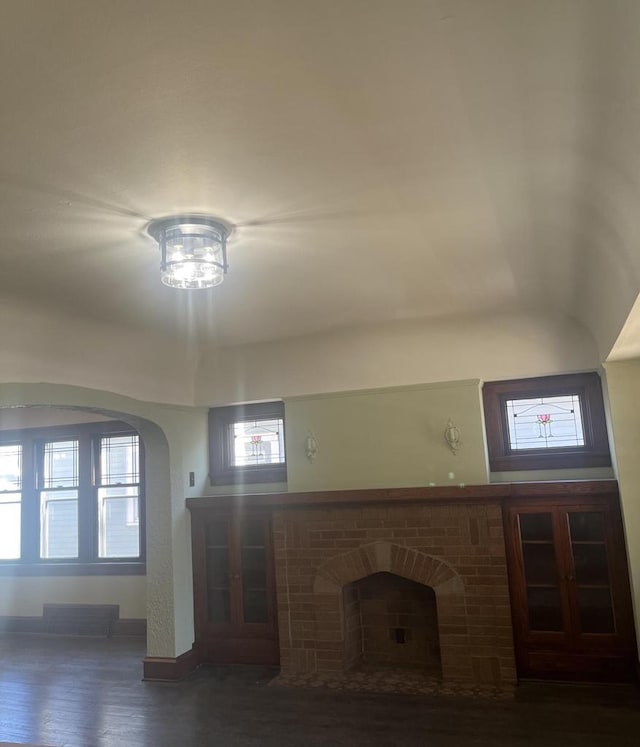 unfurnished living room with a brick fireplace and wood finished floors