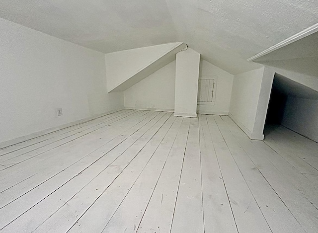 bonus room featuring lofted ceiling, a textured ceiling, and wood-type flooring