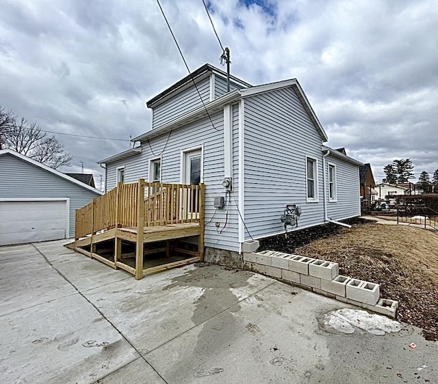 view of home's exterior featuring an outbuilding, a patio area, a detached garage, and a wooden deck