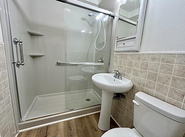 bathroom with a stall shower, toilet, and tile walls