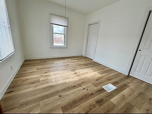 unfurnished bedroom featuring wood finished floors, visible vents, and baseboards