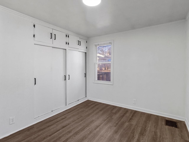 unfurnished bedroom featuring dark wood-style floors, a closet, visible vents, and baseboards