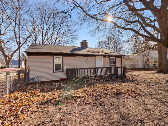 back of house with a deck, fence, and a chimney