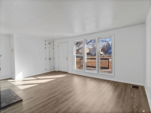 unfurnished living room with wood finished floors, visible vents, and baseboards