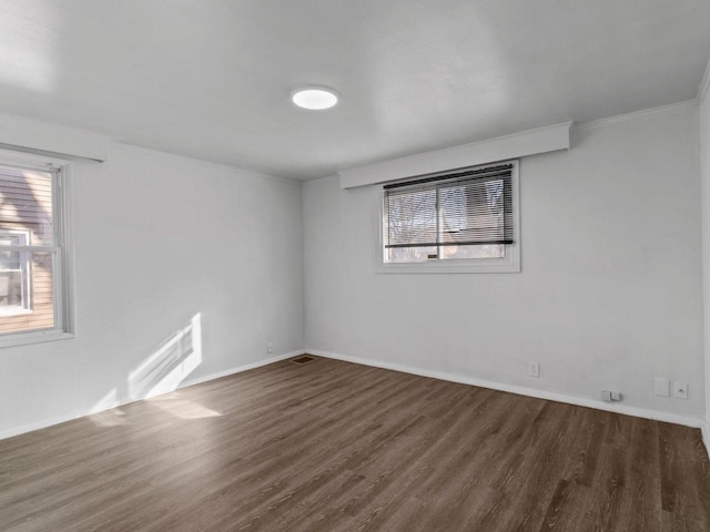 unfurnished room featuring ornamental molding, wood finished floors, visible vents, and baseboards