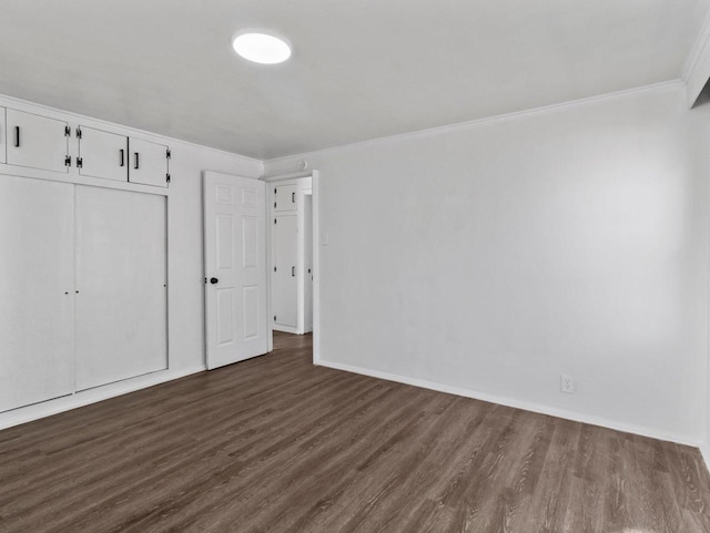 unfurnished bedroom with dark wood-type flooring, a closet, ornamental molding, and baseboards