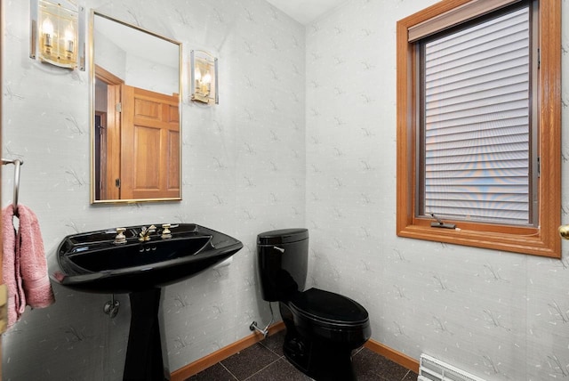 half bath with a sink, toilet, and baseboards