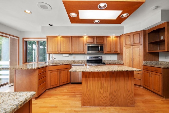 kitchen featuring stainless steel appliances, light wood finished floors, a sink, and a center island