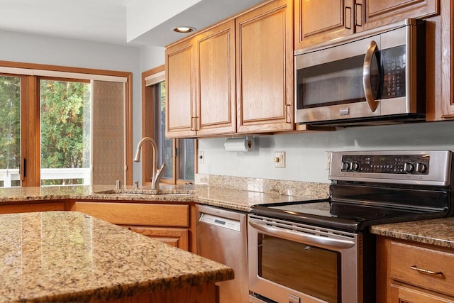 kitchen featuring stainless steel appliances, recessed lighting, a sink, and light stone countertops