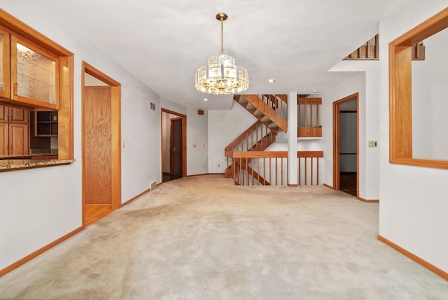 spare room featuring a notable chandelier, carpet, and baseboards