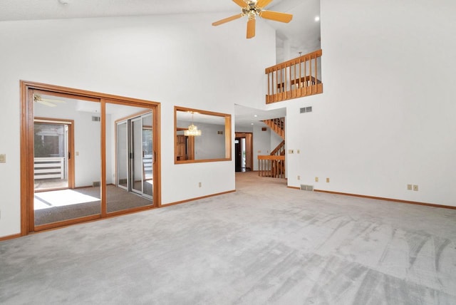 unfurnished living room with carpet, stairs, visible vents, and ceiling fan with notable chandelier