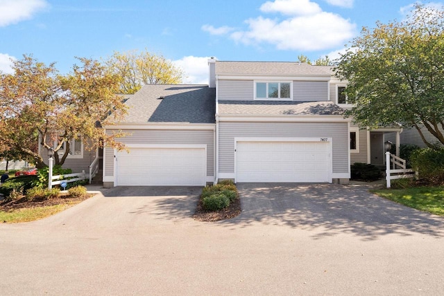 view of front of house with a garage, driveway, and roof with shingles