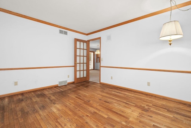 unfurnished room with ornamental molding, french doors, hardwood / wood-style flooring, and visible vents