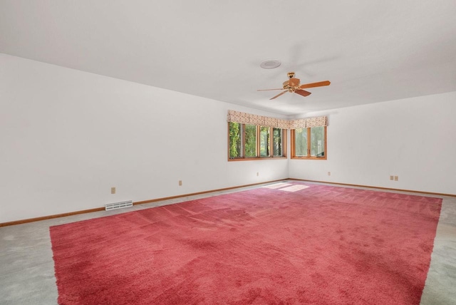 empty room with carpet floors, visible vents, ceiling fan, and baseboards