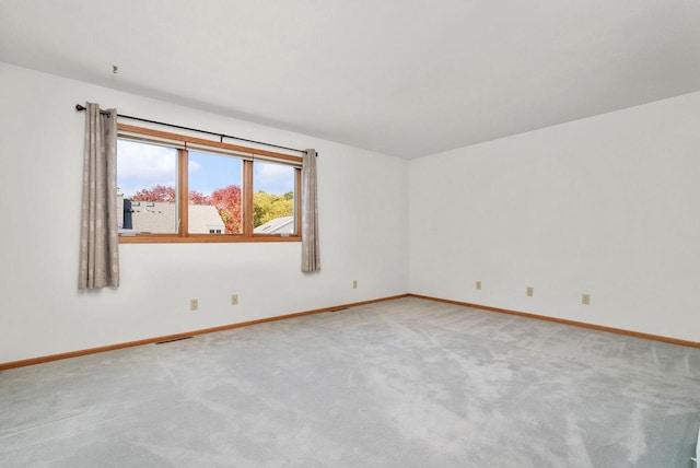 spare room with visible vents, baseboards, and light colored carpet