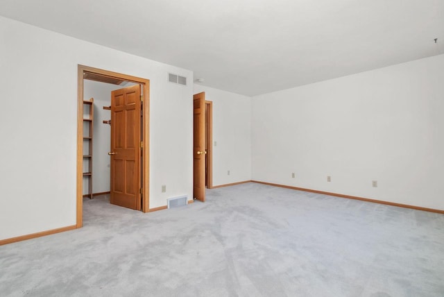 spare room with light carpet, visible vents, and baseboards